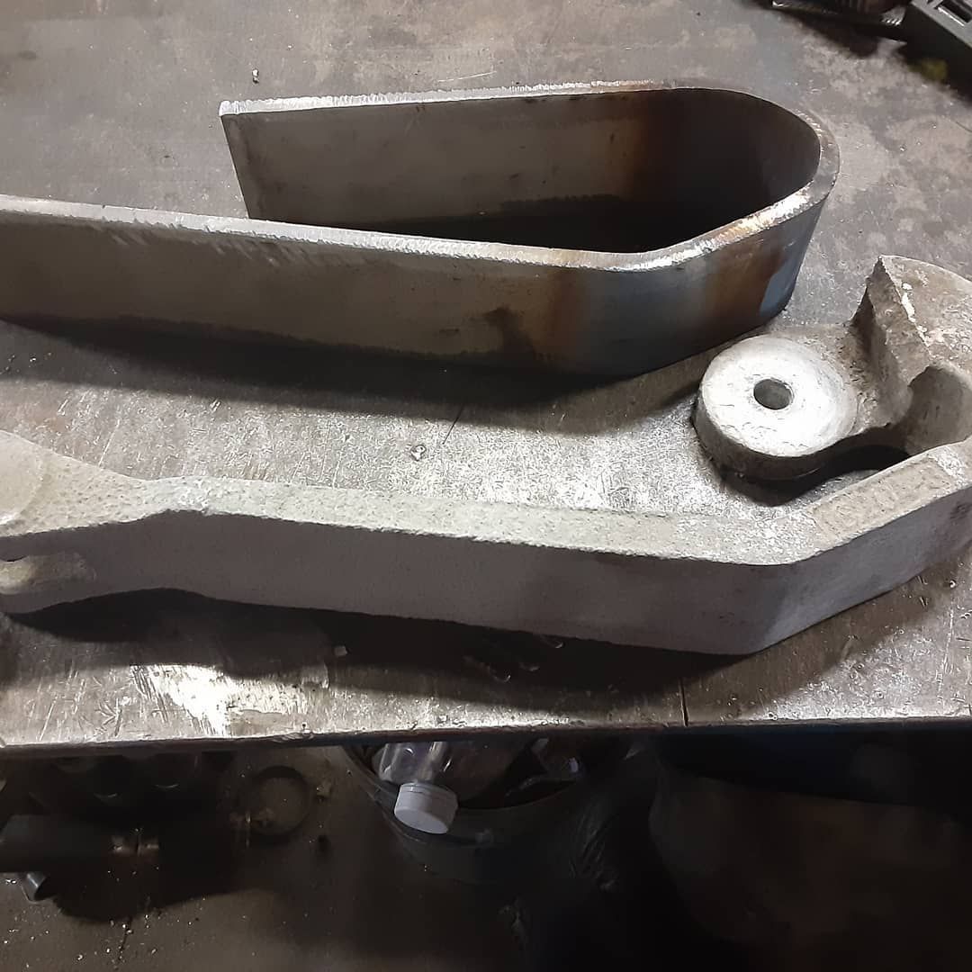 Two metal pieces are sitting on top of a metal table.