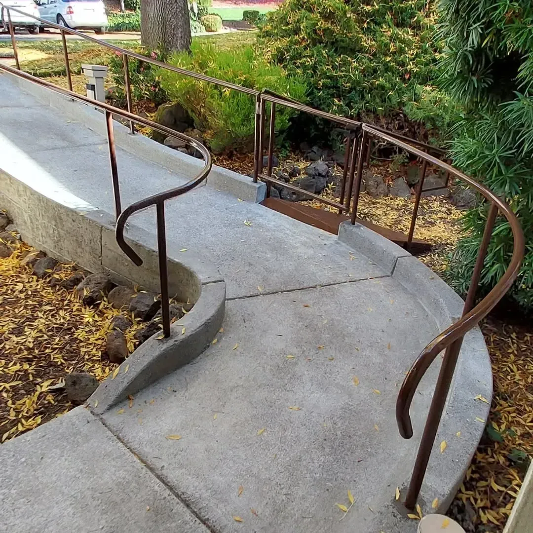 A concrete walkway with a metal railing and stairs