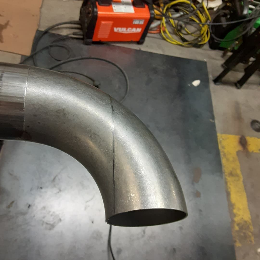 A metal pipe is sitting on a table next to a vulcan welding machine