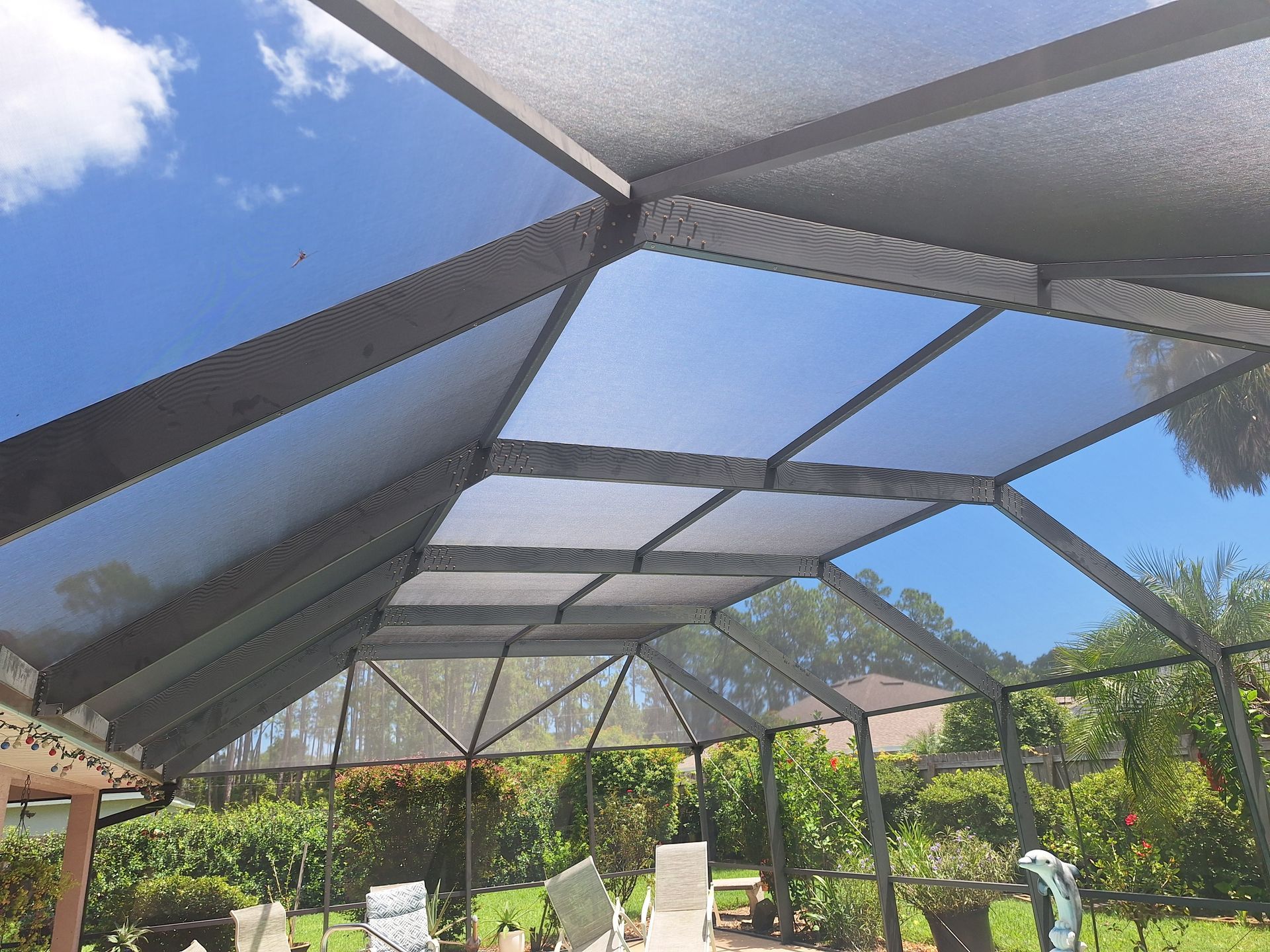 Screened patio roof with sky view and yard background.