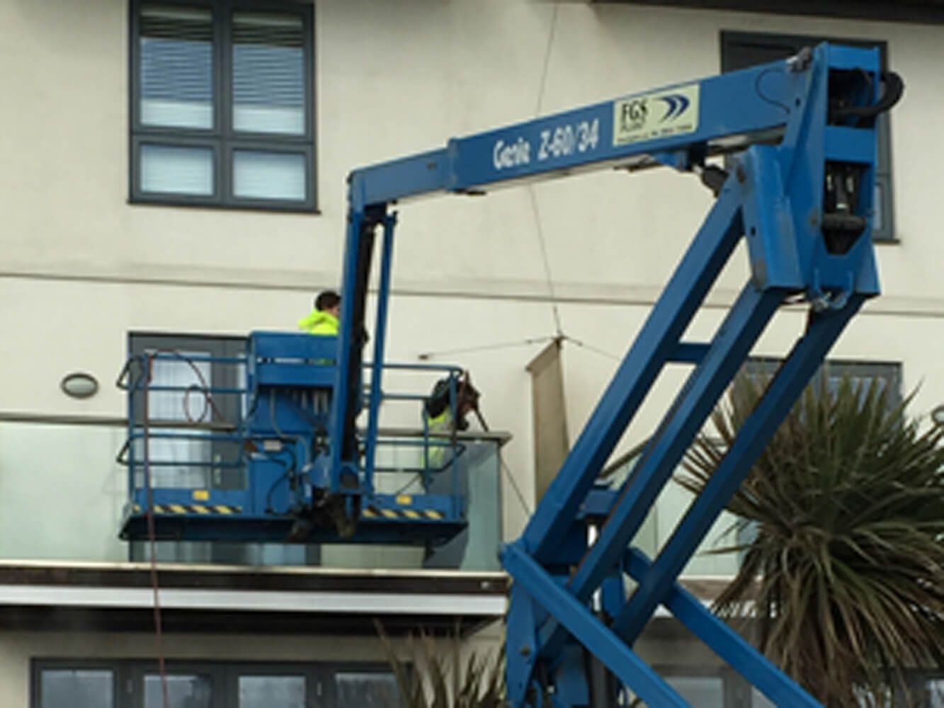 man cleaning outside of a building on a crane