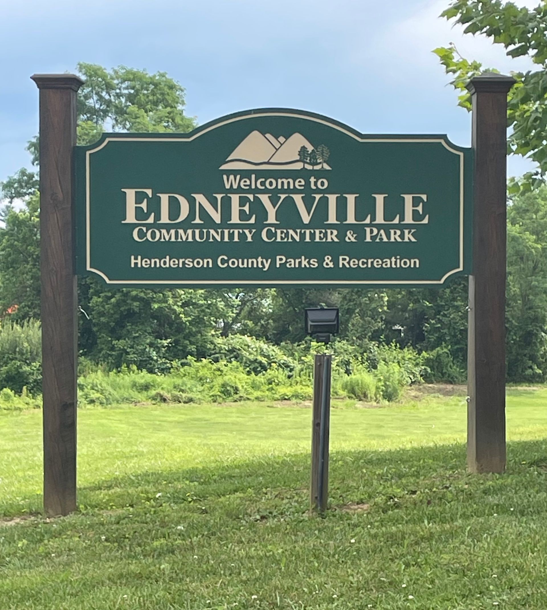 A green sign that says welcome to edneyville community center & park