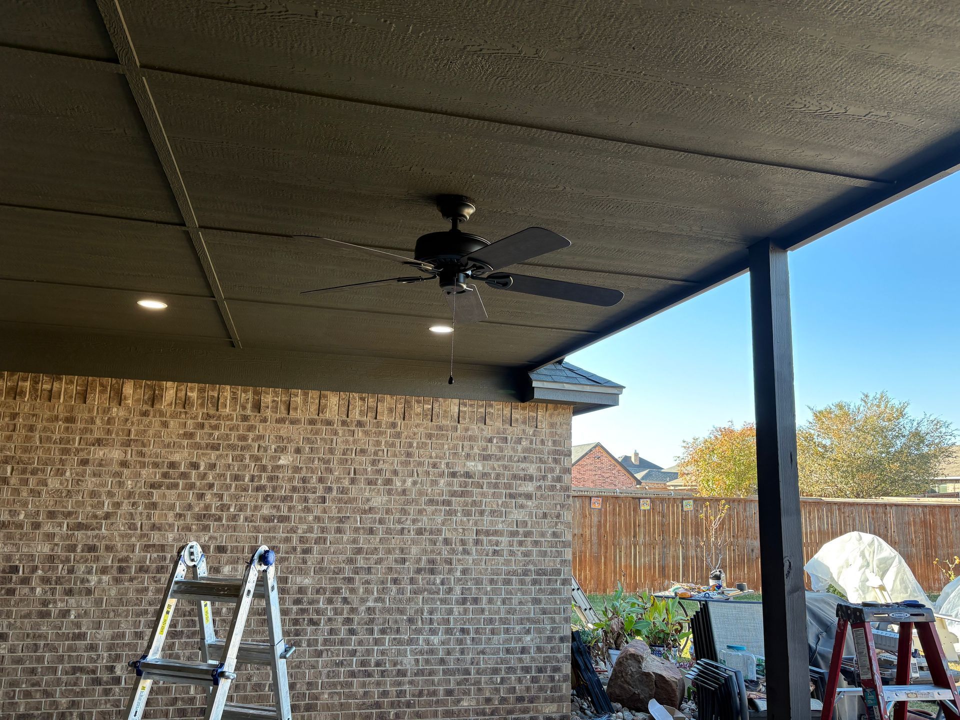 Outdoor patio with a brick wall, ceiling fan, and recessed lights.