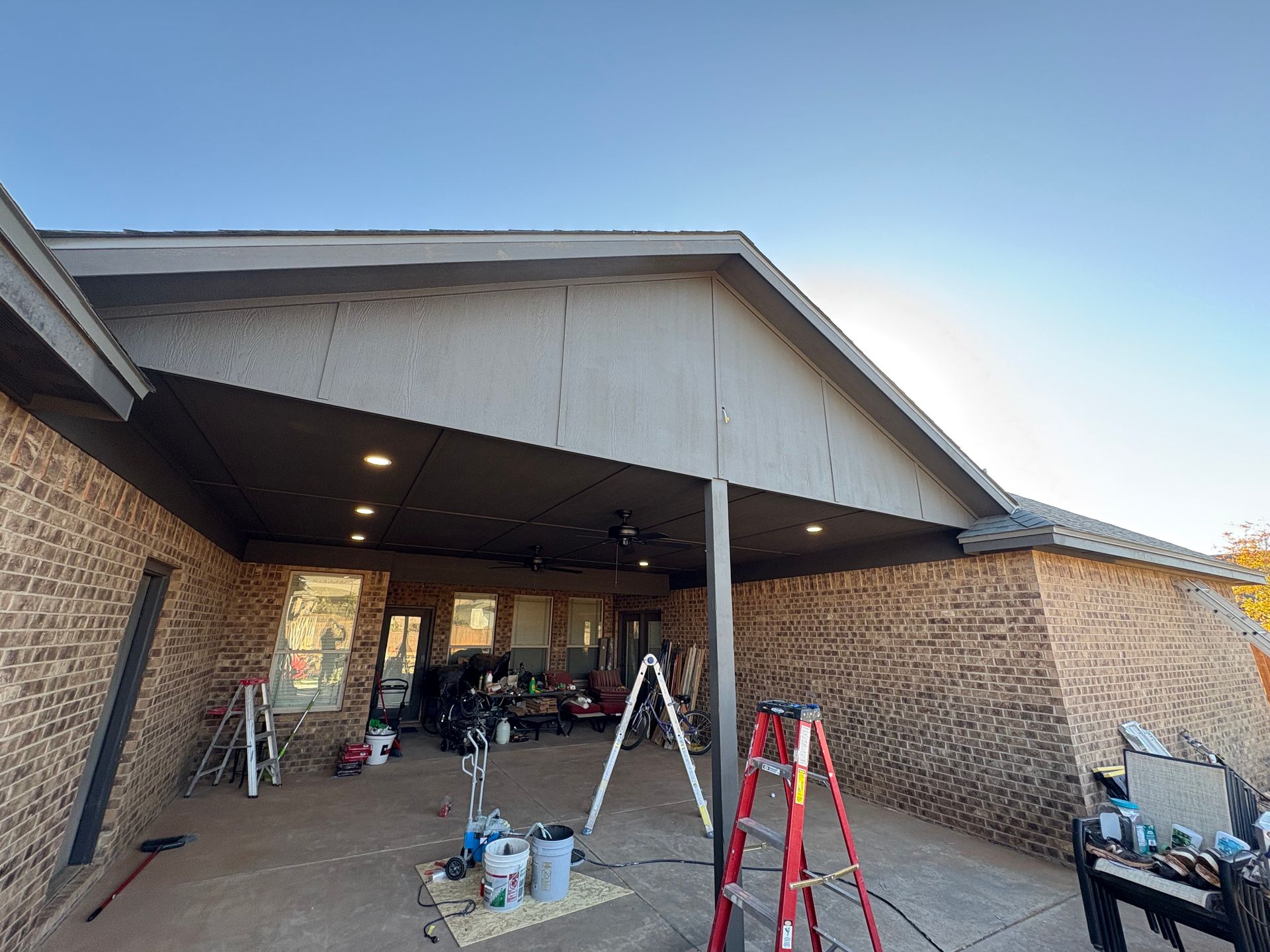 Brick patio with a covered section, tools and equipment present.
