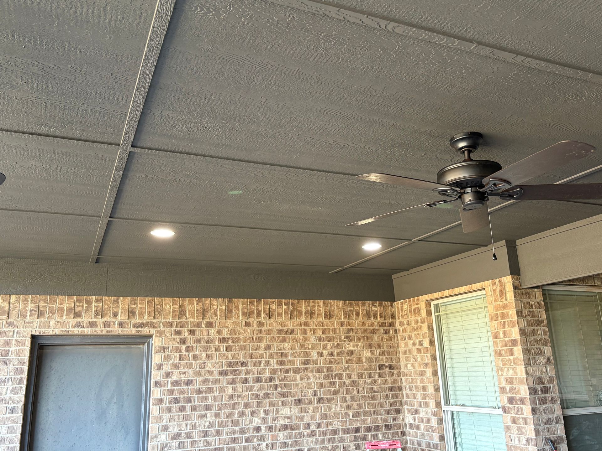 Brick patio with grey ceiling, recessed lights, and ceiling fan.