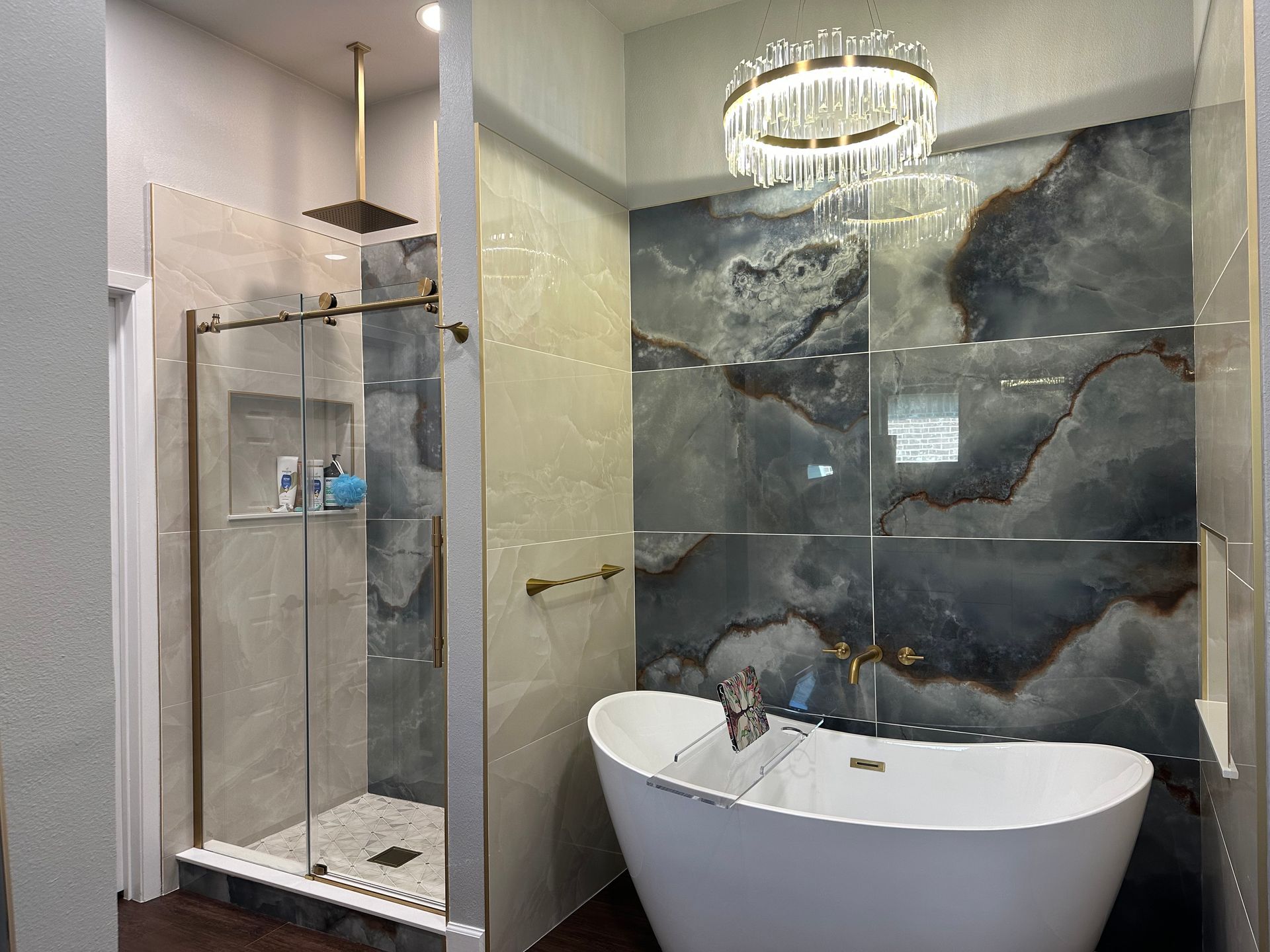 Modern bathroom with a glass shower, a freestanding tub, and a decorative tile wall.