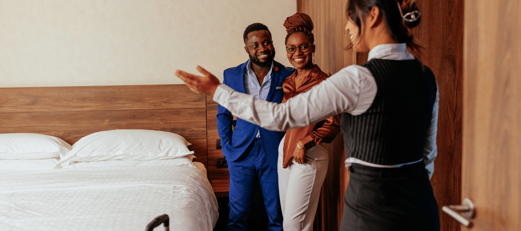 hotel housekeeper showing happy couple to their clean hotel room