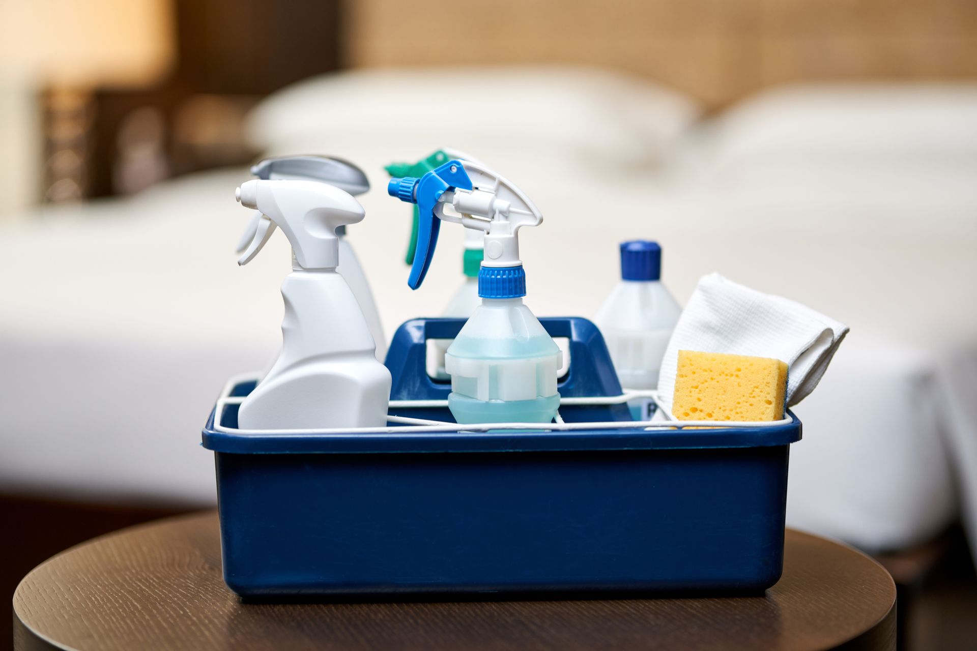 a blue cleaning caddy filled with cleaning supplies is sitting on a wooden table .