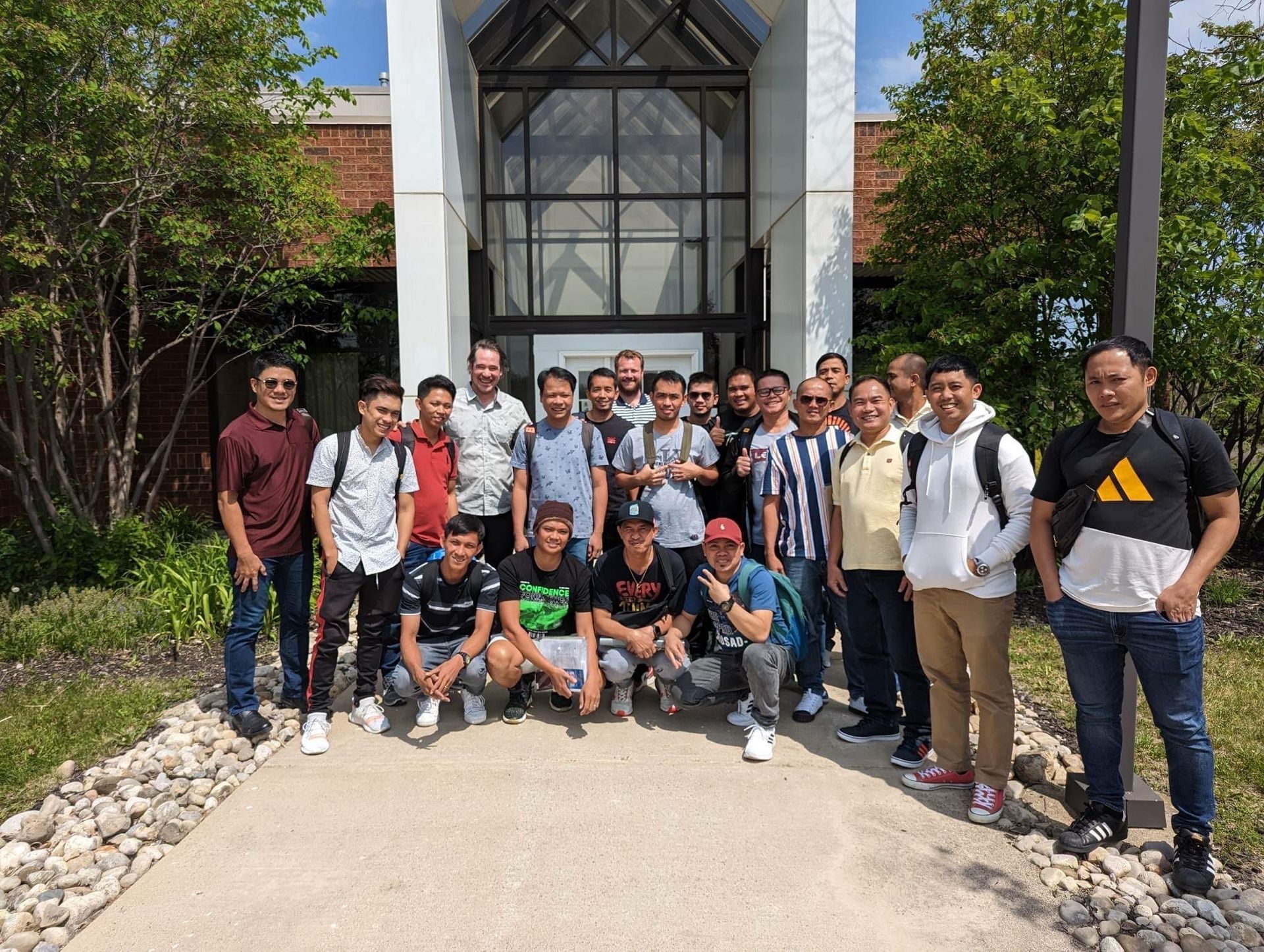 Un groupe de jeunes hommes pose pour une photo devant un bâtiment.