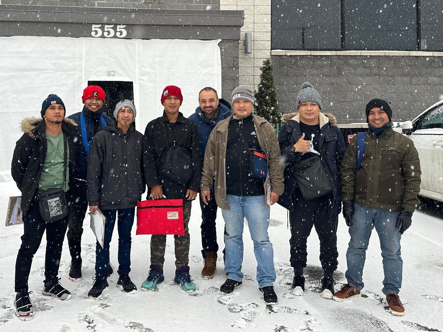 Un groupe d'hommes se tient dans la neige devant un bâtiment.