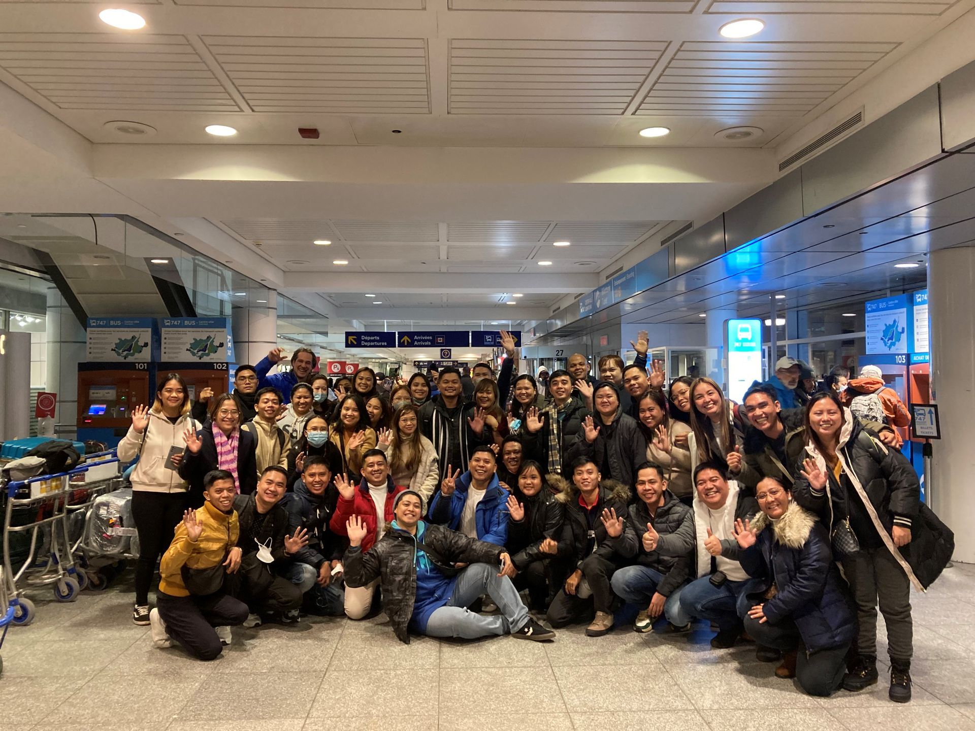Un grand groupe de personnes pose pour une photo dans un aéroport.