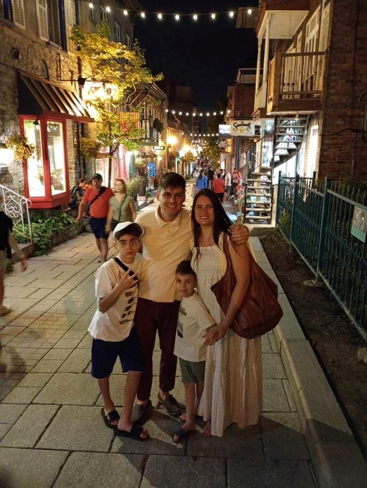 Une famille pose pour une photo sur un trottoir la nuit.