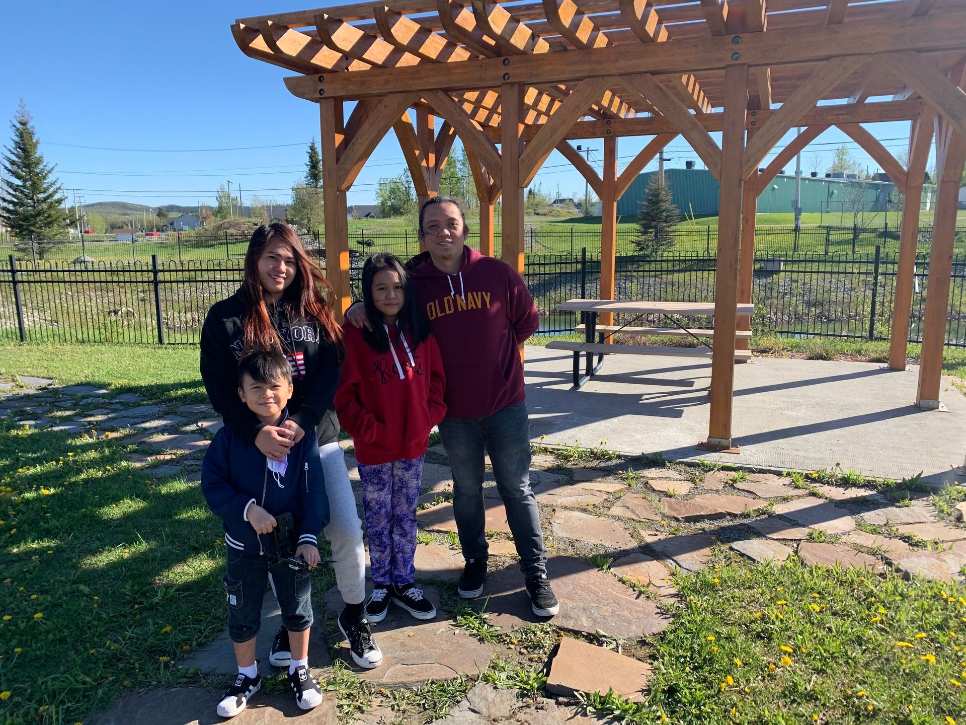Une famille pose pour une photo devant une pergola en bois.