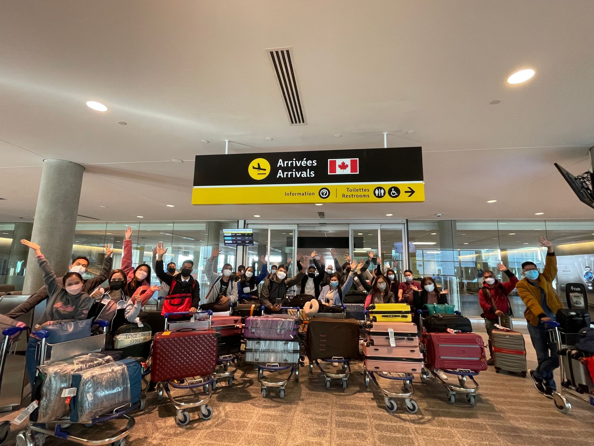 Un groupe de personnes se tient devant un panneau indiquant arrivées arrivées.