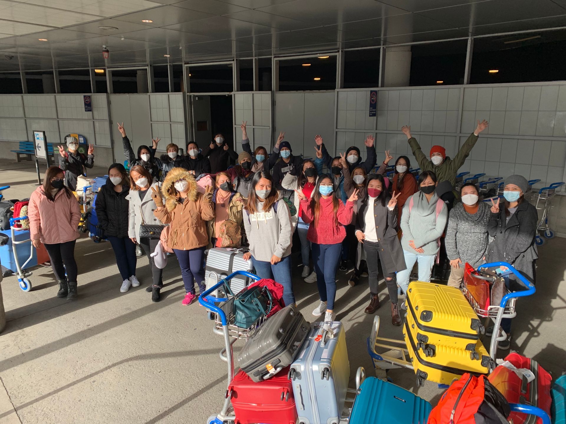 Un groupe de personnes portant des masques posent pour une photo dans un aéroport.