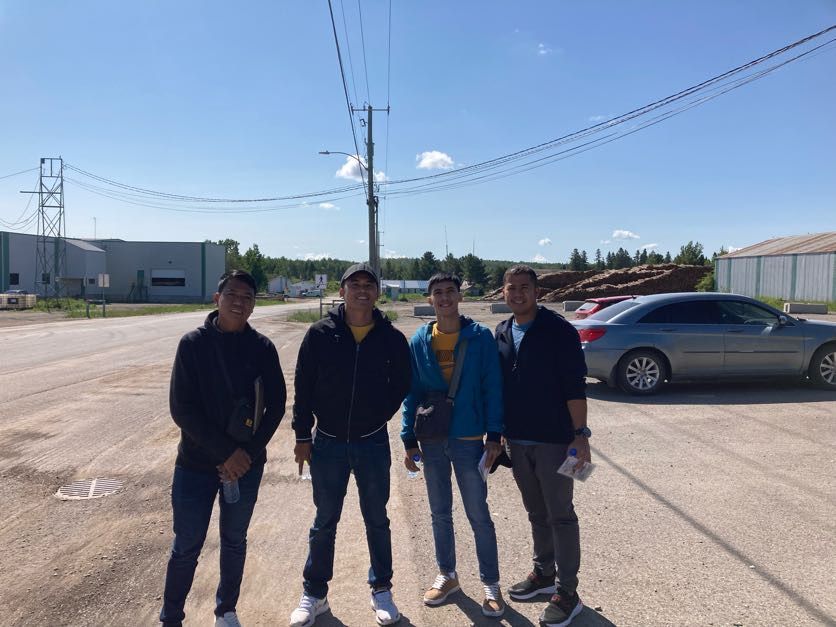 Un groupe de jeunes hommes se tiennent côte à côte sur un parking.