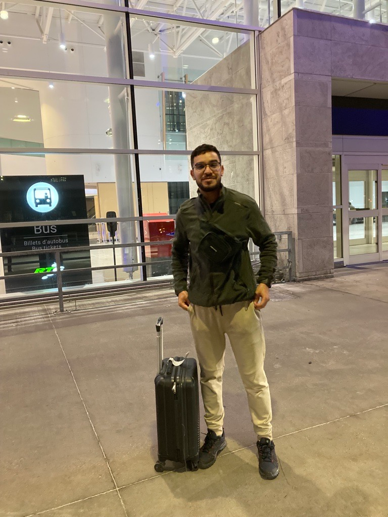 Un homme se tient à côté d'une valise dans un aéroport.