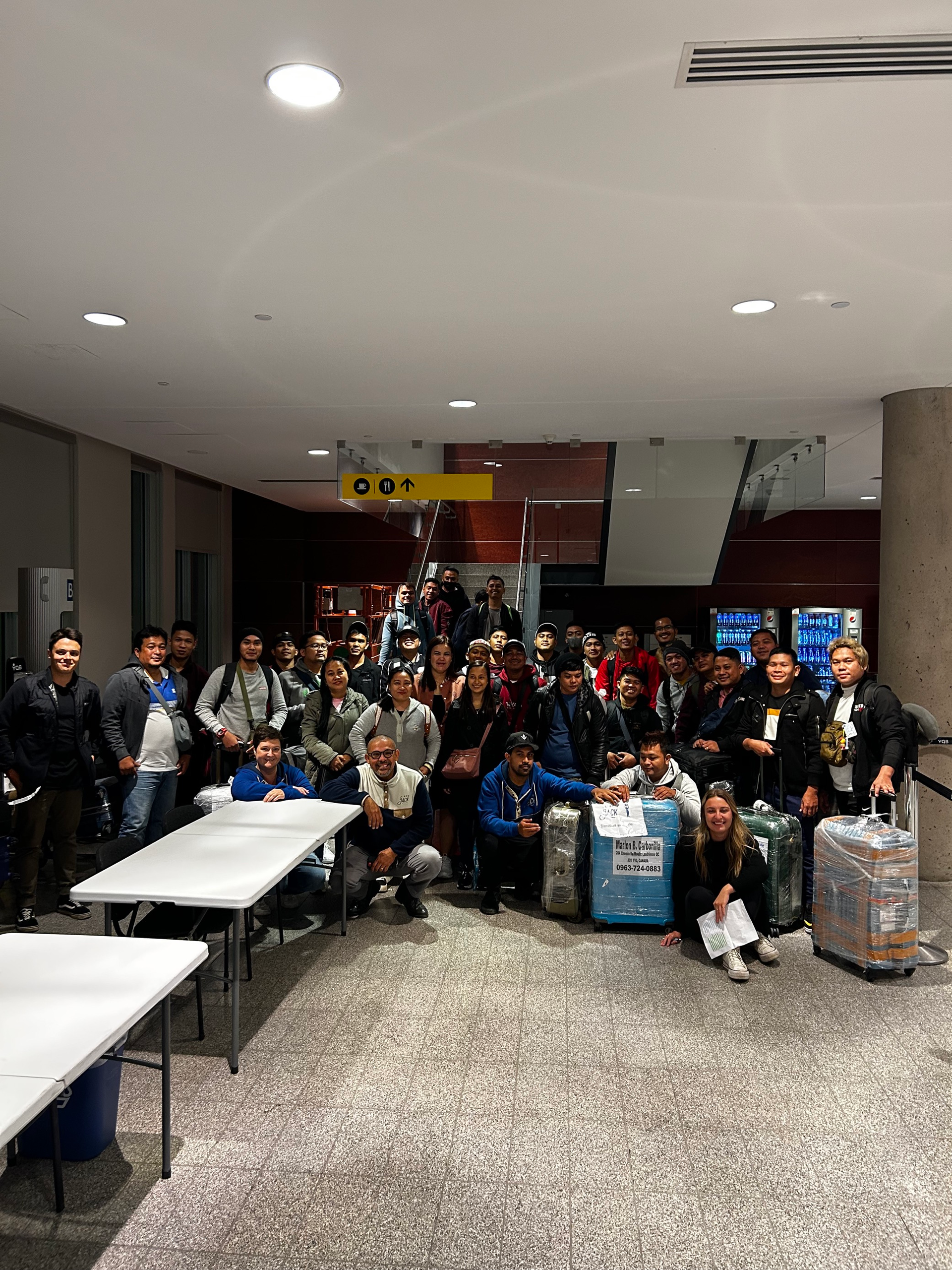 Un groupe de personnes pose pour une photo dans une pièce avec des bagages.