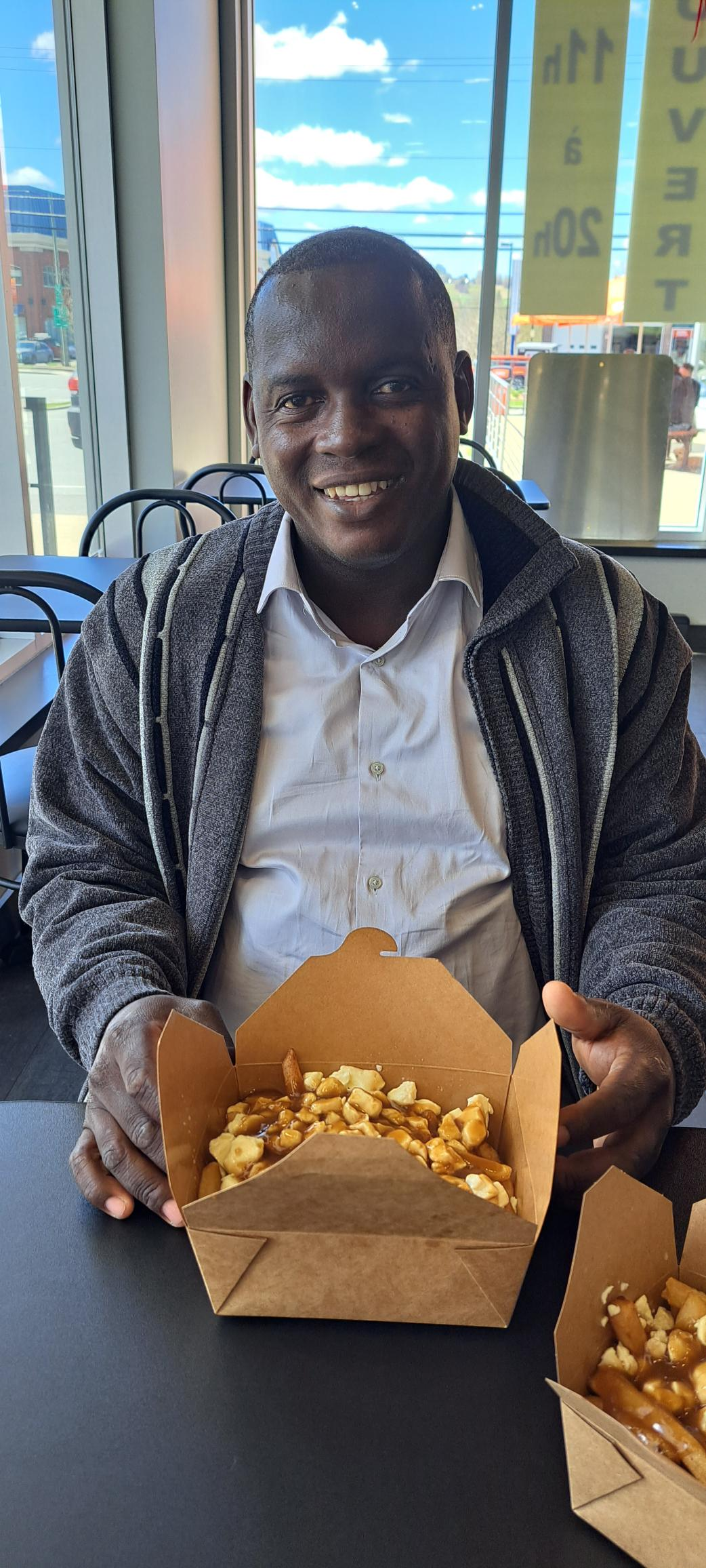 Un homme est assis à une table et tient une boîte de nourriture.