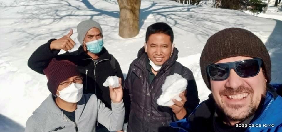 Un groupe d'hommes portant des masques et des lunettes de soleil se tiennent debout dans la neige.