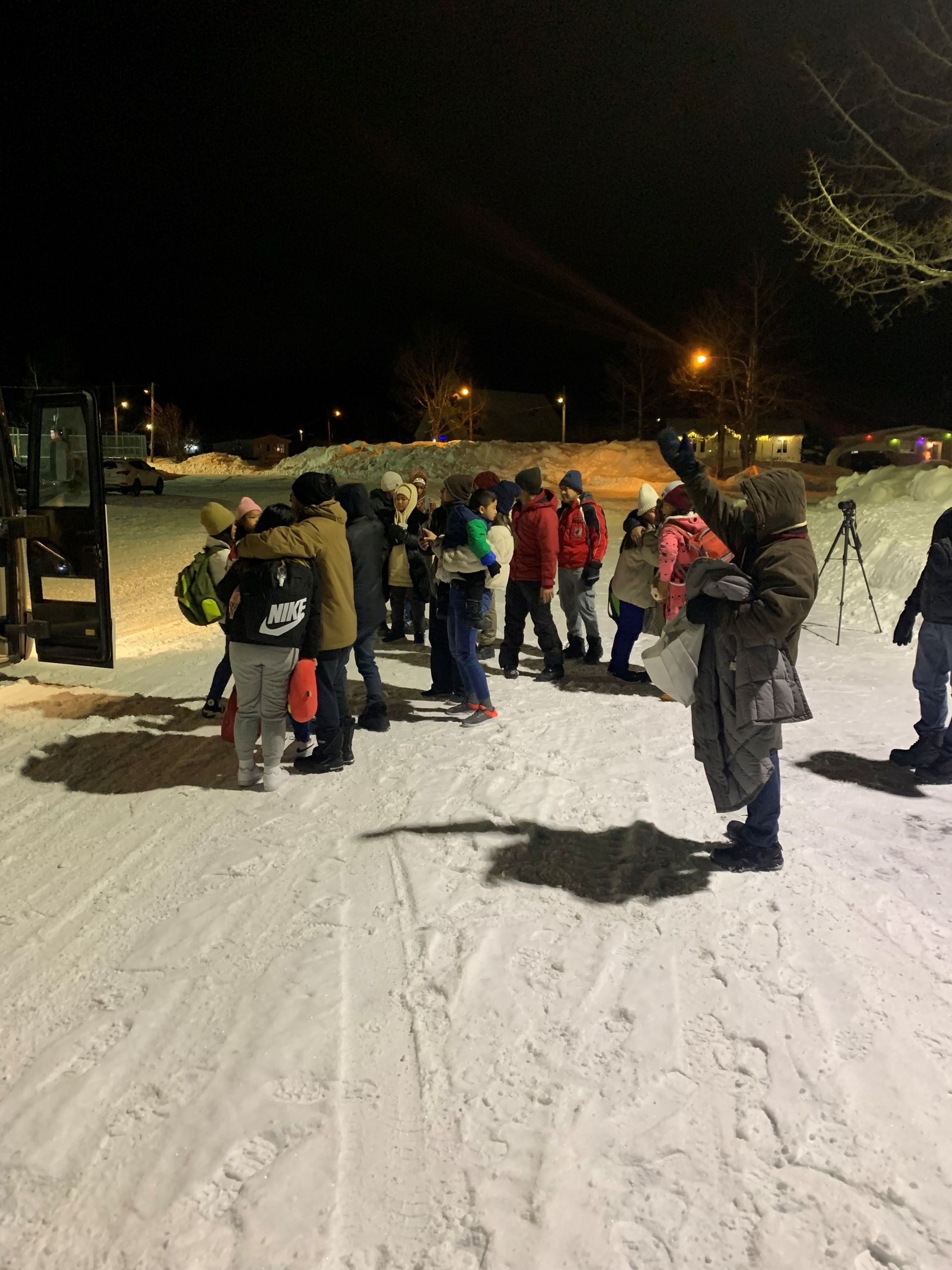 Un groupe de personnes se tient dans la neige la nuit.