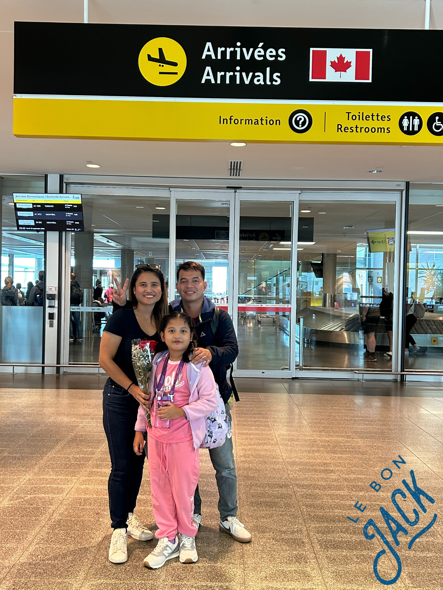 Une famille debout devant un panneau indiquant arrivées