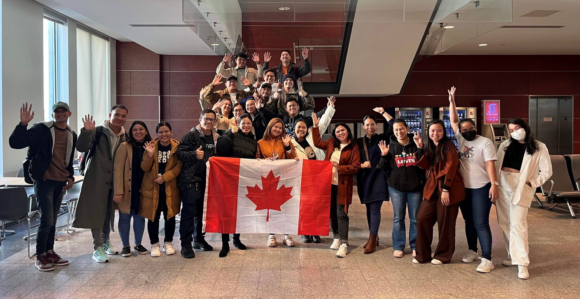 Un groupe de personnes pose pour une photo tout en tenant un drapeau canadien.