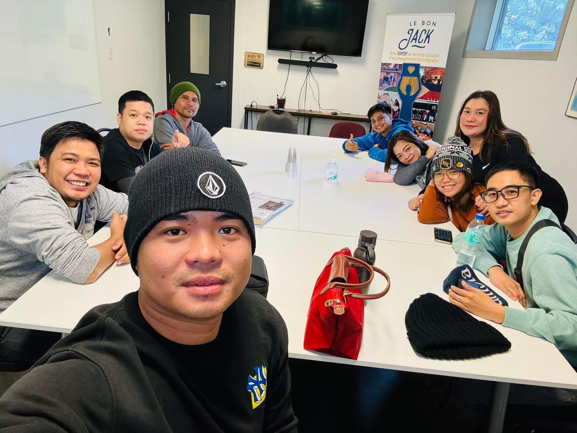 Un homme prend un selfie avec un groupe de personnes assises autour d'une table.