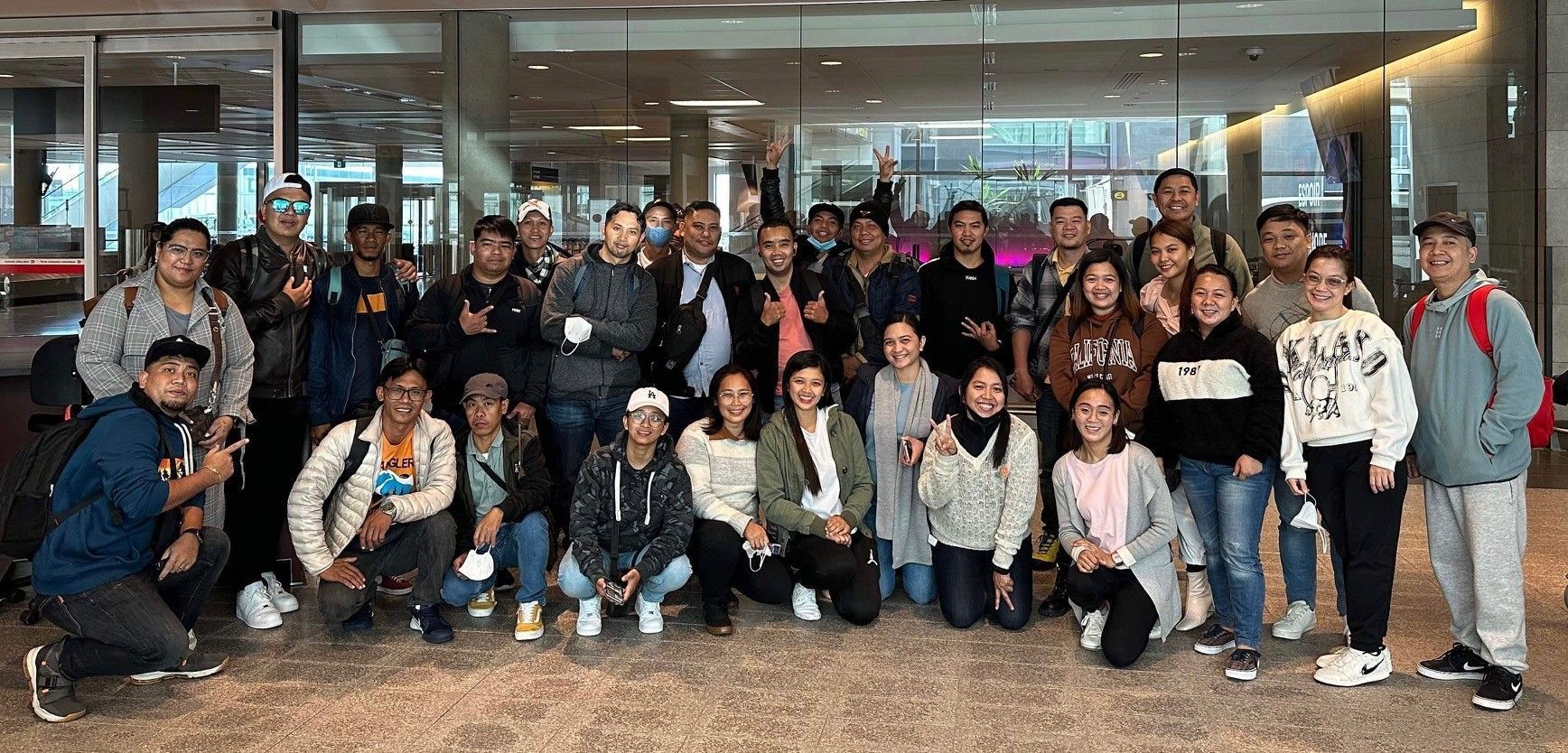 Un grand groupe de personnes pose pour une photo dans un aéroport.