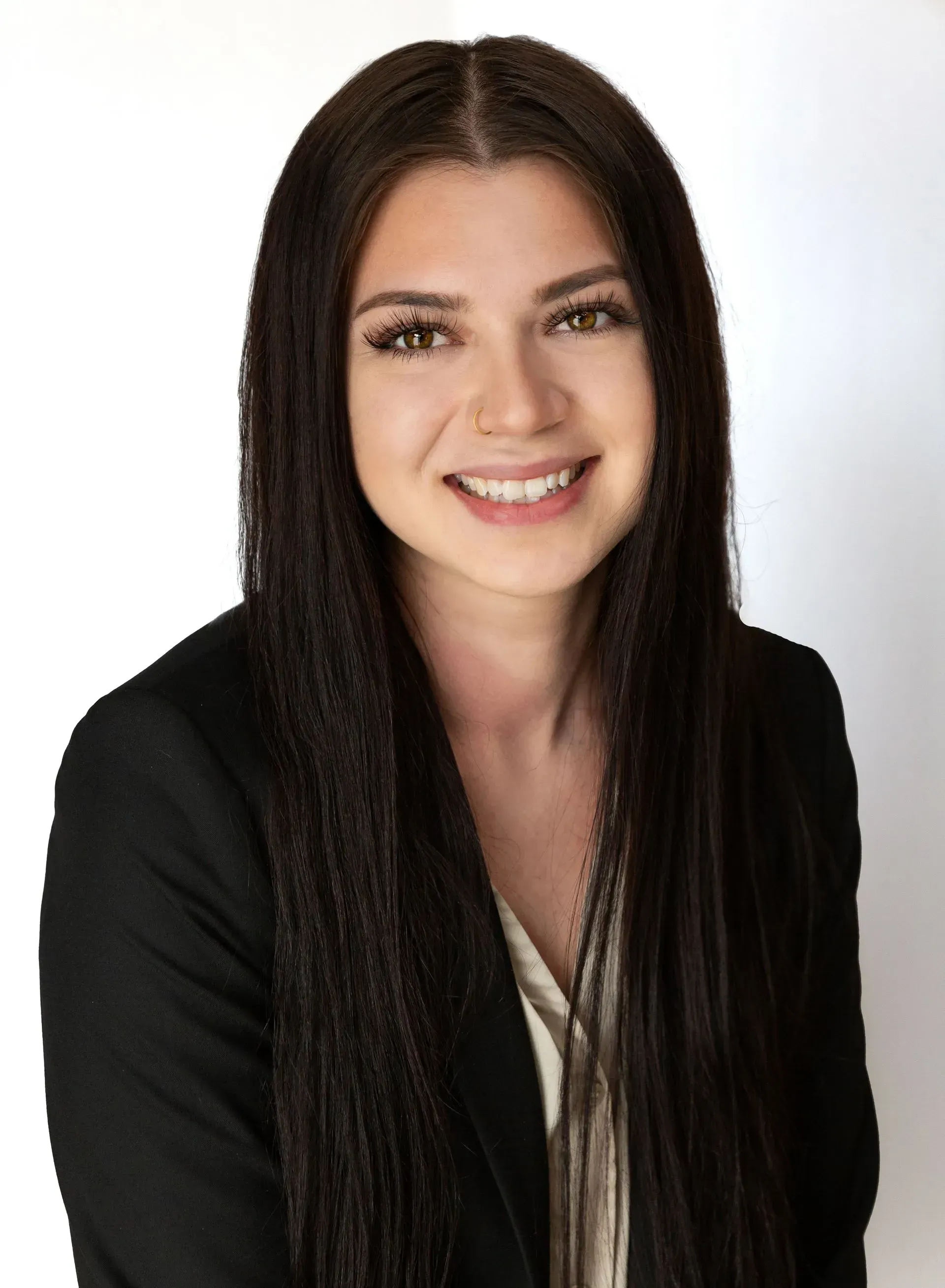 A woman with long hair is wearing a black jacket and smiling.