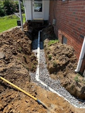 Sink with running water, surrounded by a wooden counter, a dish rack, and cleaning supplies.
