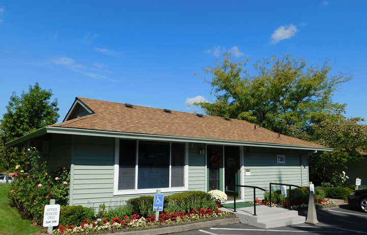 Green office building with a wheelchair access ramp, blue sky overhead.