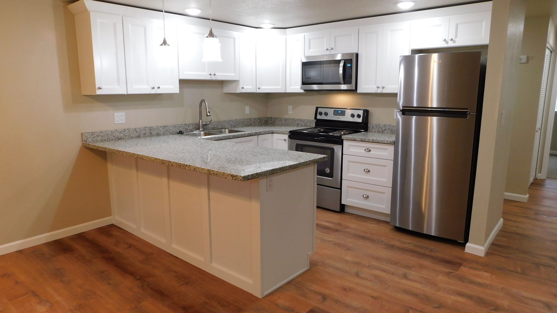 Newly renovated kitchen with white cabinets, granite countertops, stainless steel appliances, and hardwood floors.