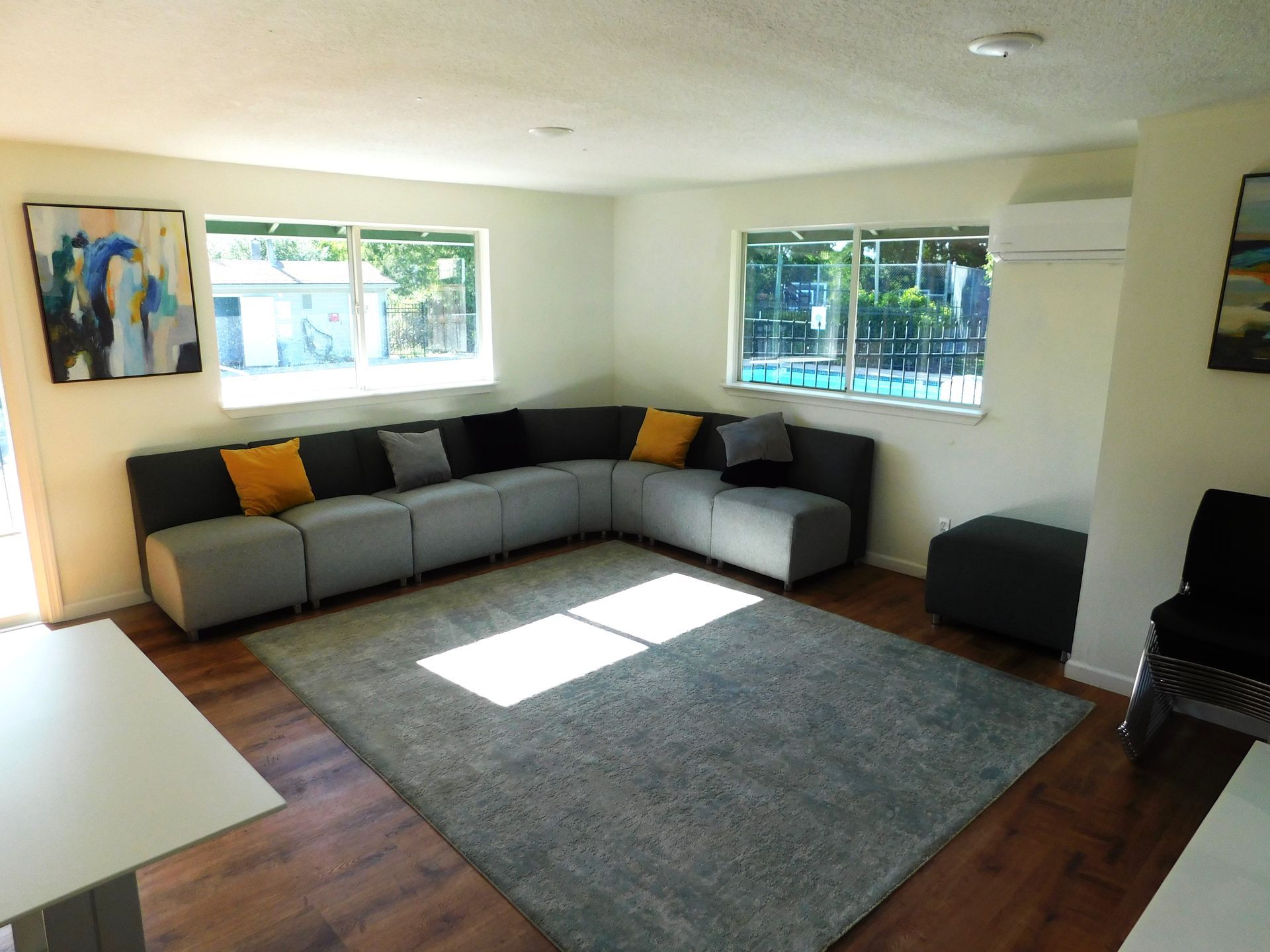 A modern living room with a gray sectional sofa, a gray rug, and large windows.
