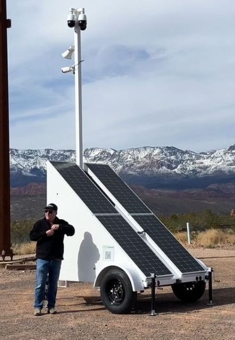 A man standing next to a trailer with solar panels on it