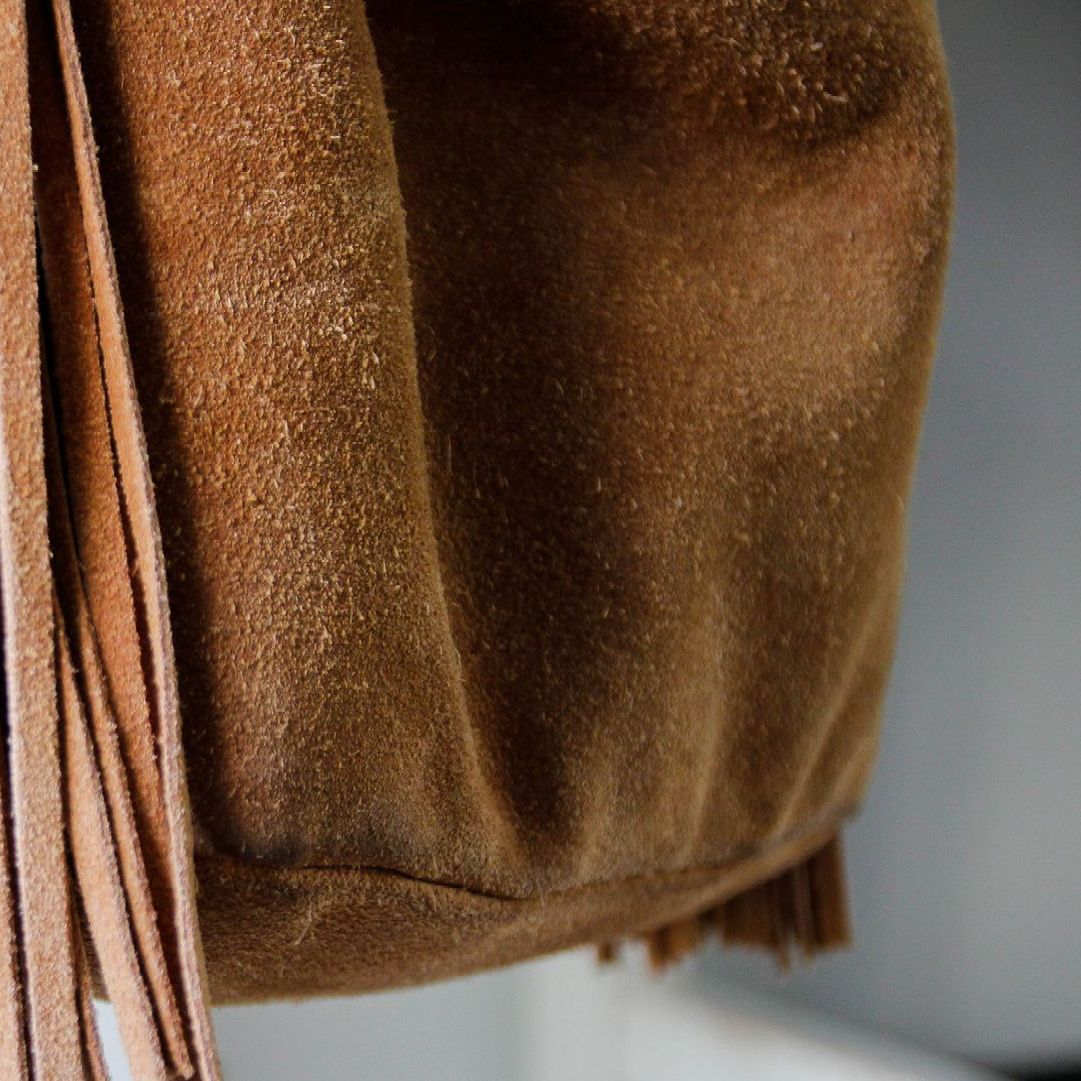 Un primo piano di una borsa in pelle scamosciata marrone con frange