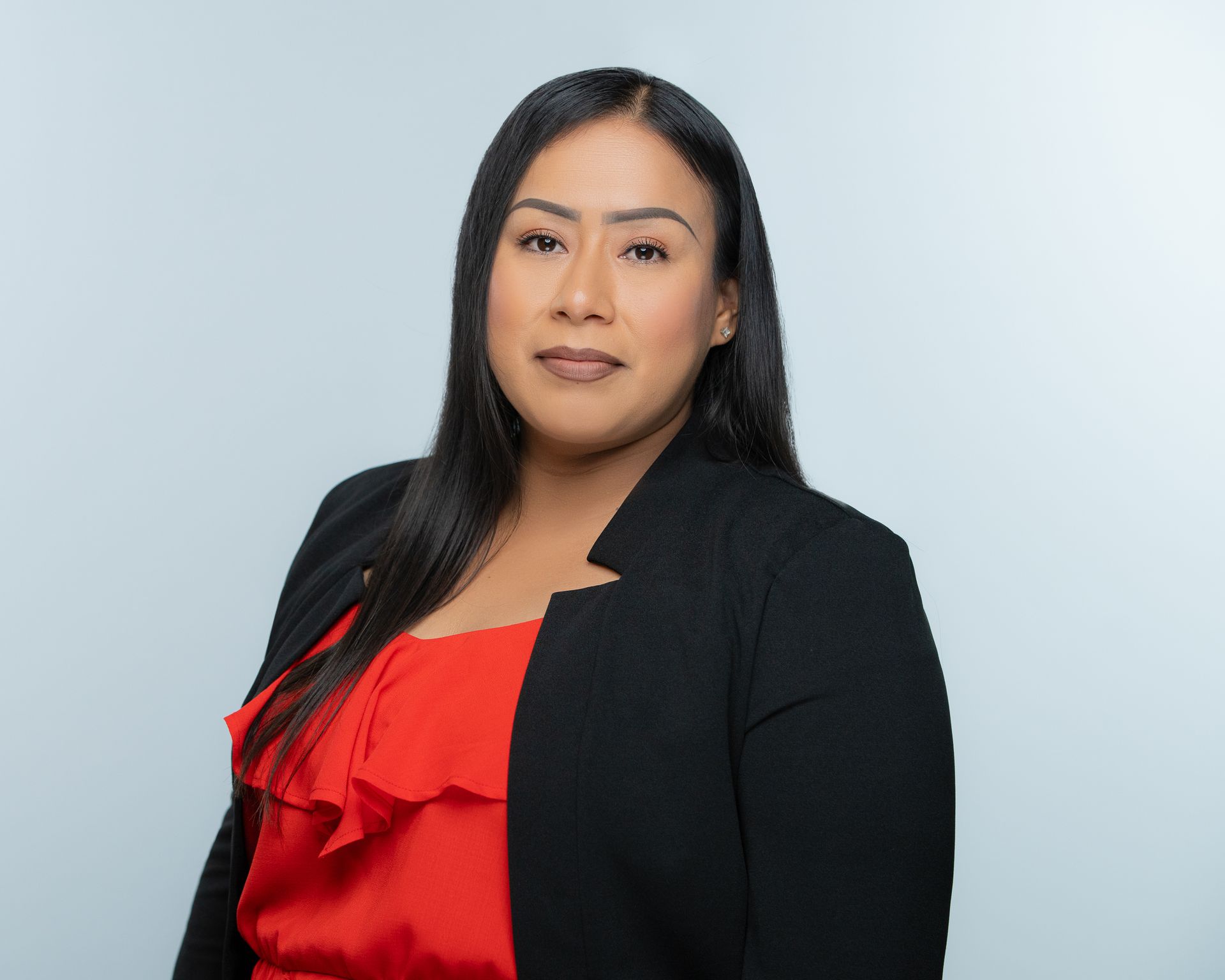 A woman is sitting at a desk with a laptop and a vase of flowers.