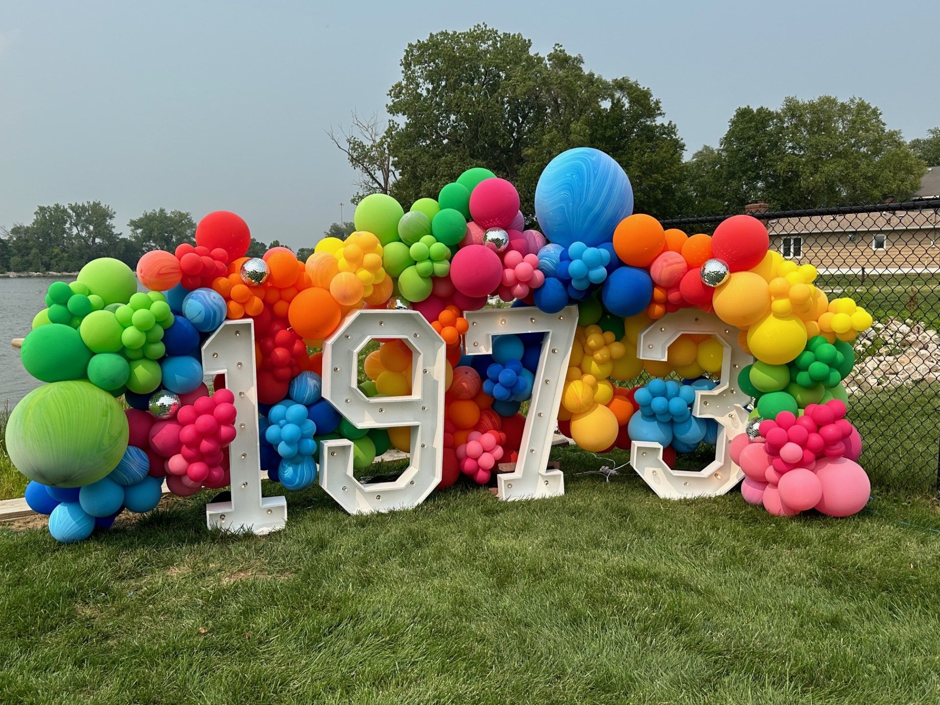 A bunch of colorful balloons are sitting on top of a lush green field.