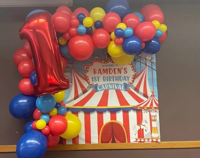 A carnival themed birthday party with balloons and a sign