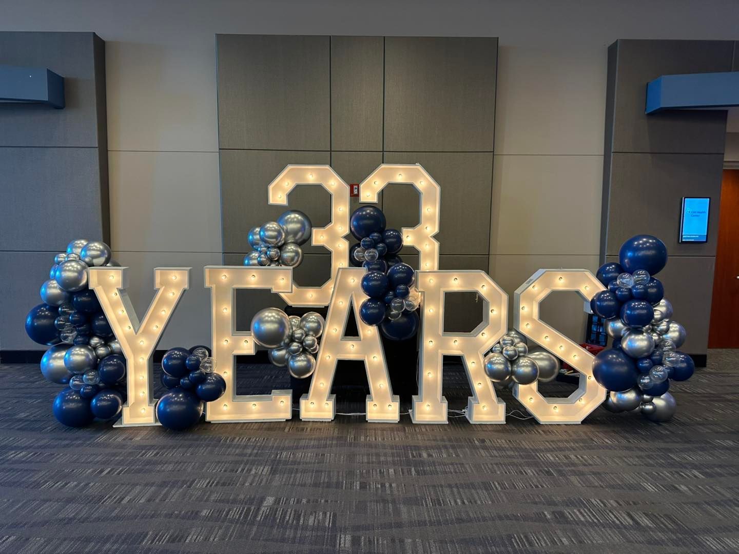 A large sign that says 33 years is surrounded by blue and silver balloons.