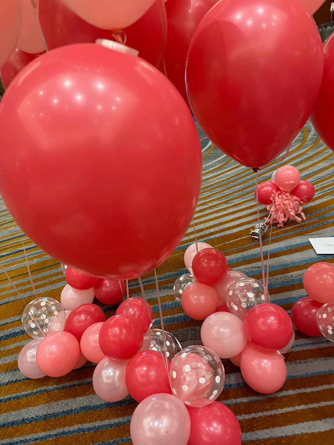 A bunch of red and pink balloons are sitting on the floor.