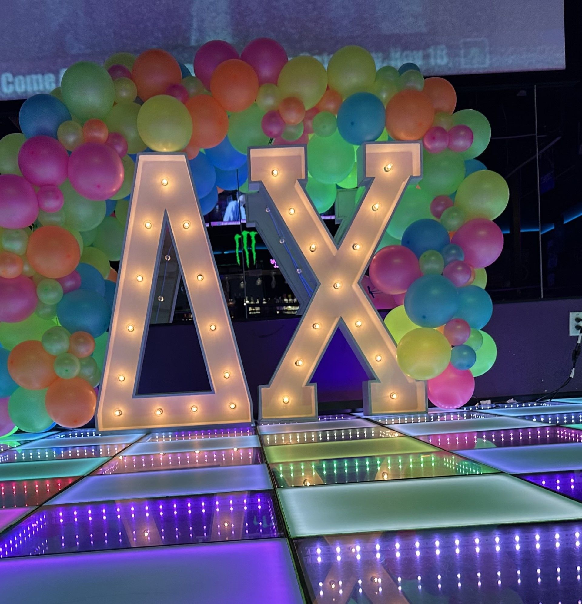 The letter a and x are lit up in front of balloons
