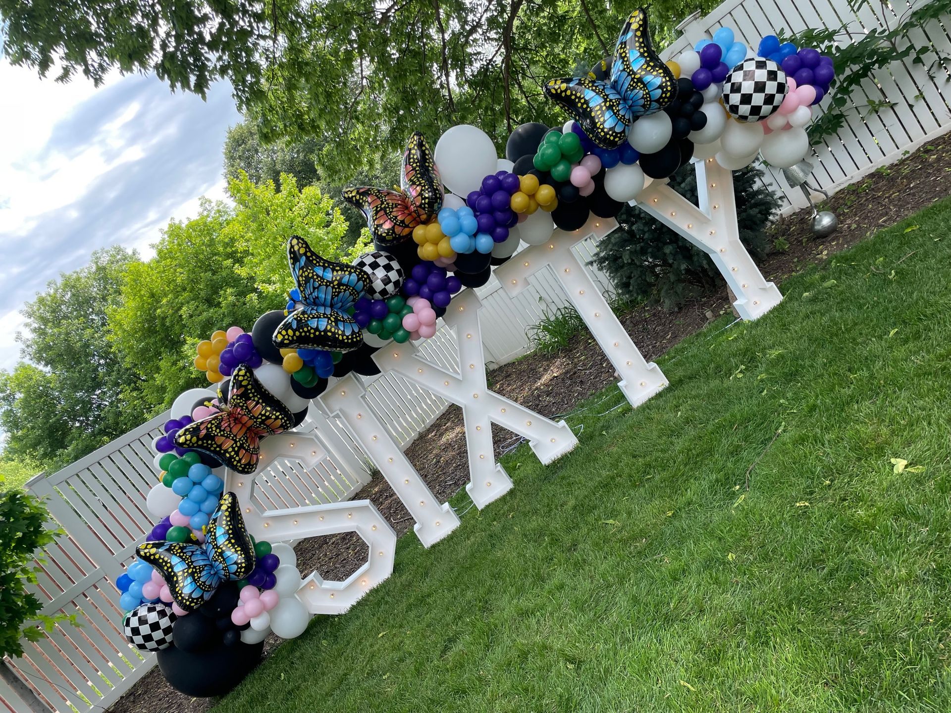A bunch of balloons are sitting on top of a sign that says sixty.