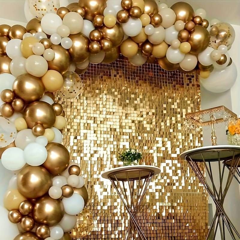 A room filled with gold and white balloons and a table.