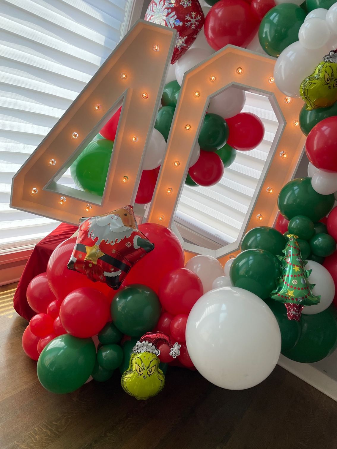 A number 40 is surrounded by red , green and white balloons.