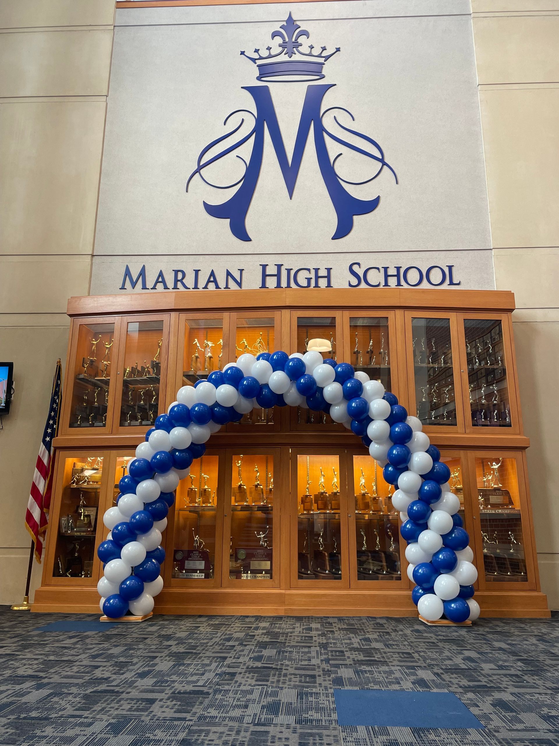 A blue and white balloon arch in front of marian high school