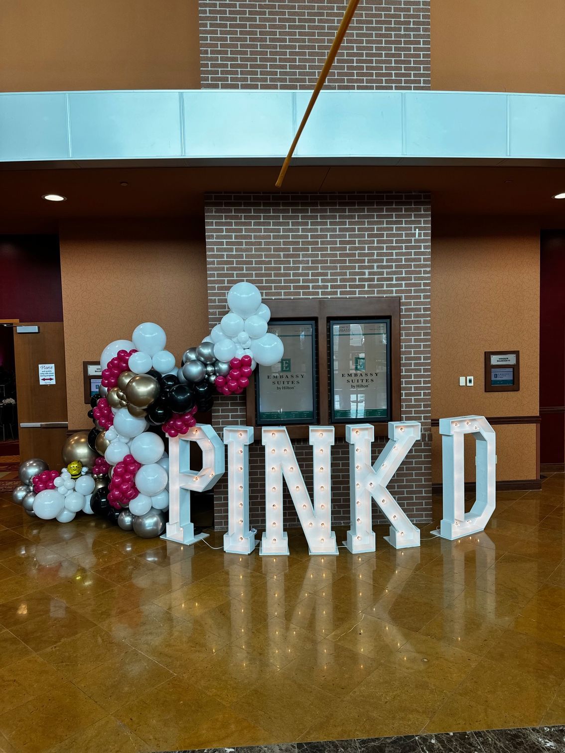A large pink d sign is surrounded by balloons