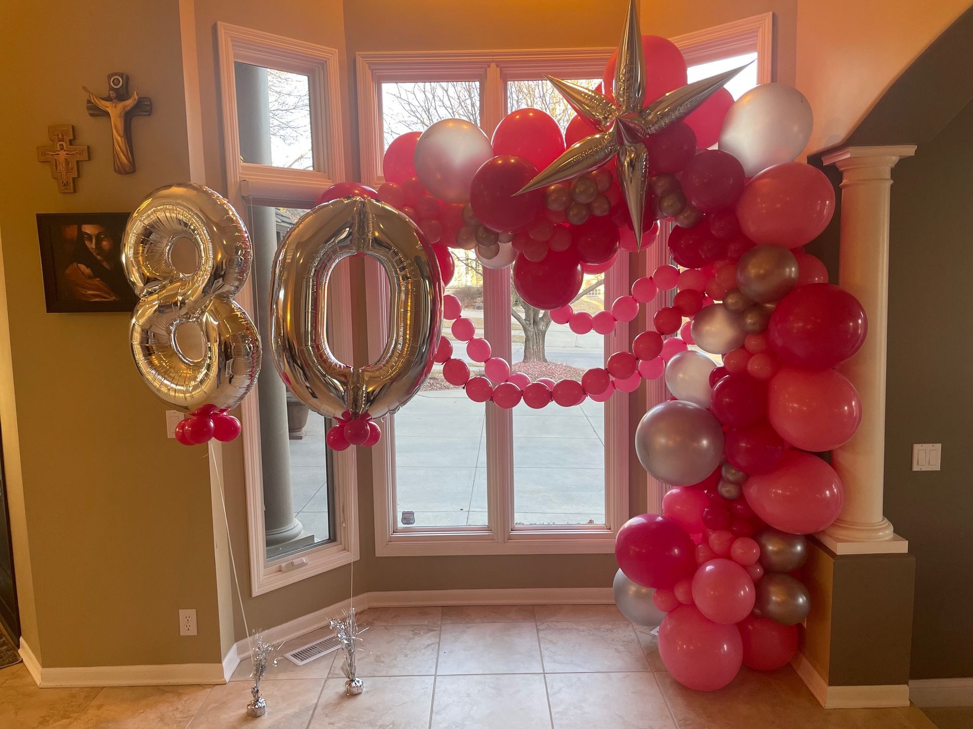 A room decorated with pink and silver balloons and a number 80 balloon.