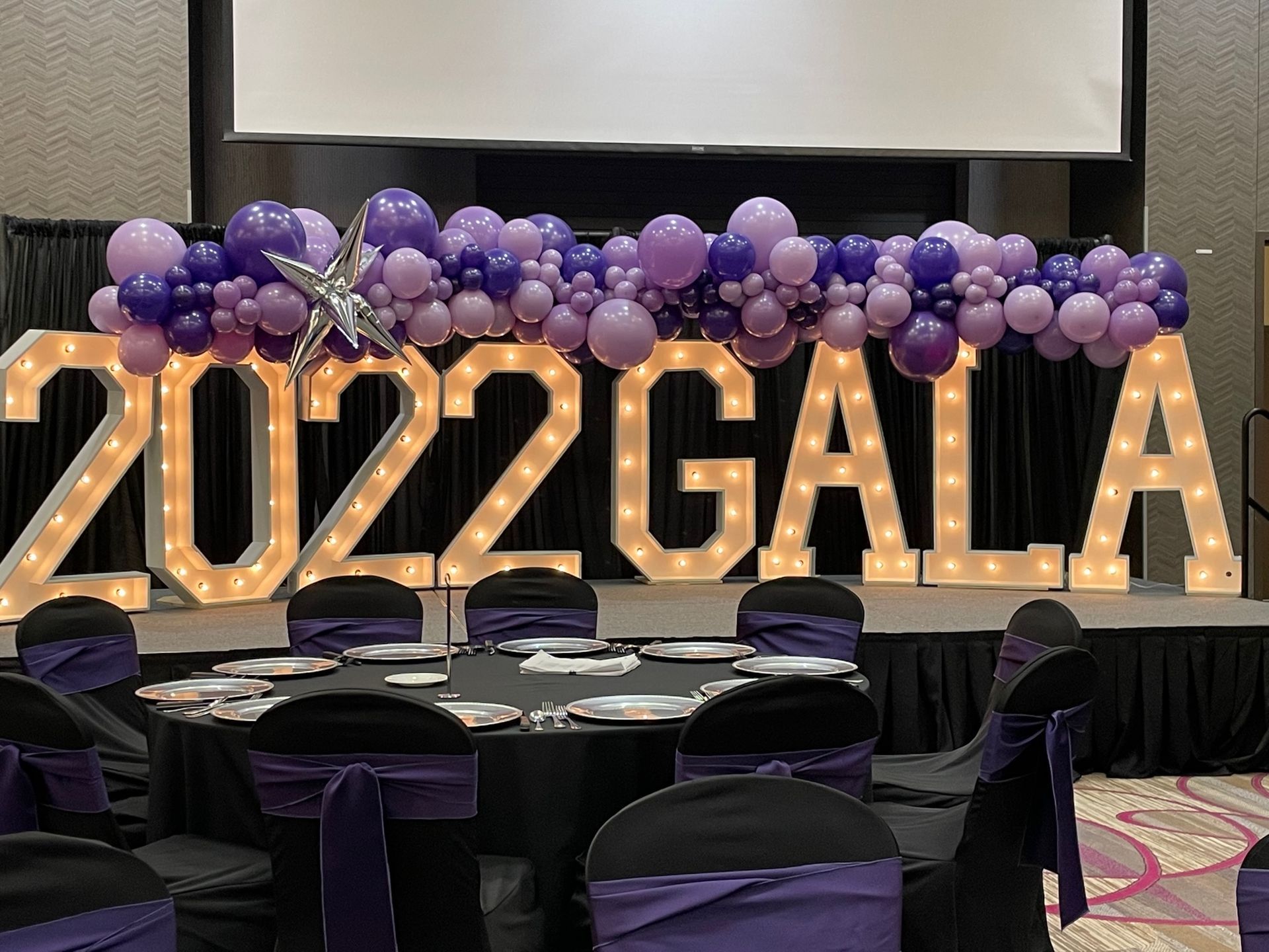 A room with tables and chairs and a sign that says 2022 gala.