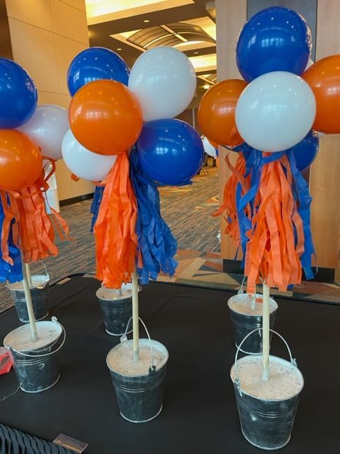 Blue white and orange balloons in buckets on a table